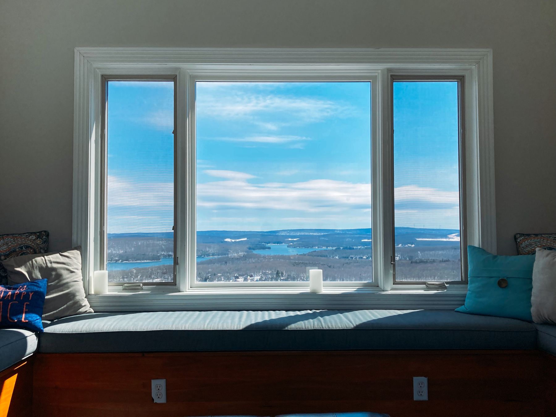Long upholstered cushion across a wide window bench with blue sky beyond