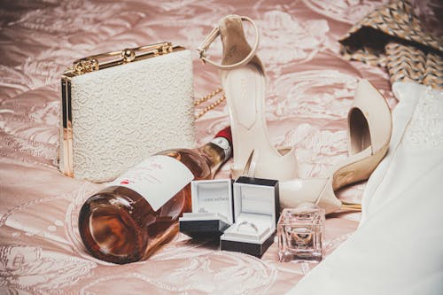 High Heels, Jewellery and Bottle of Wine on the Bed 