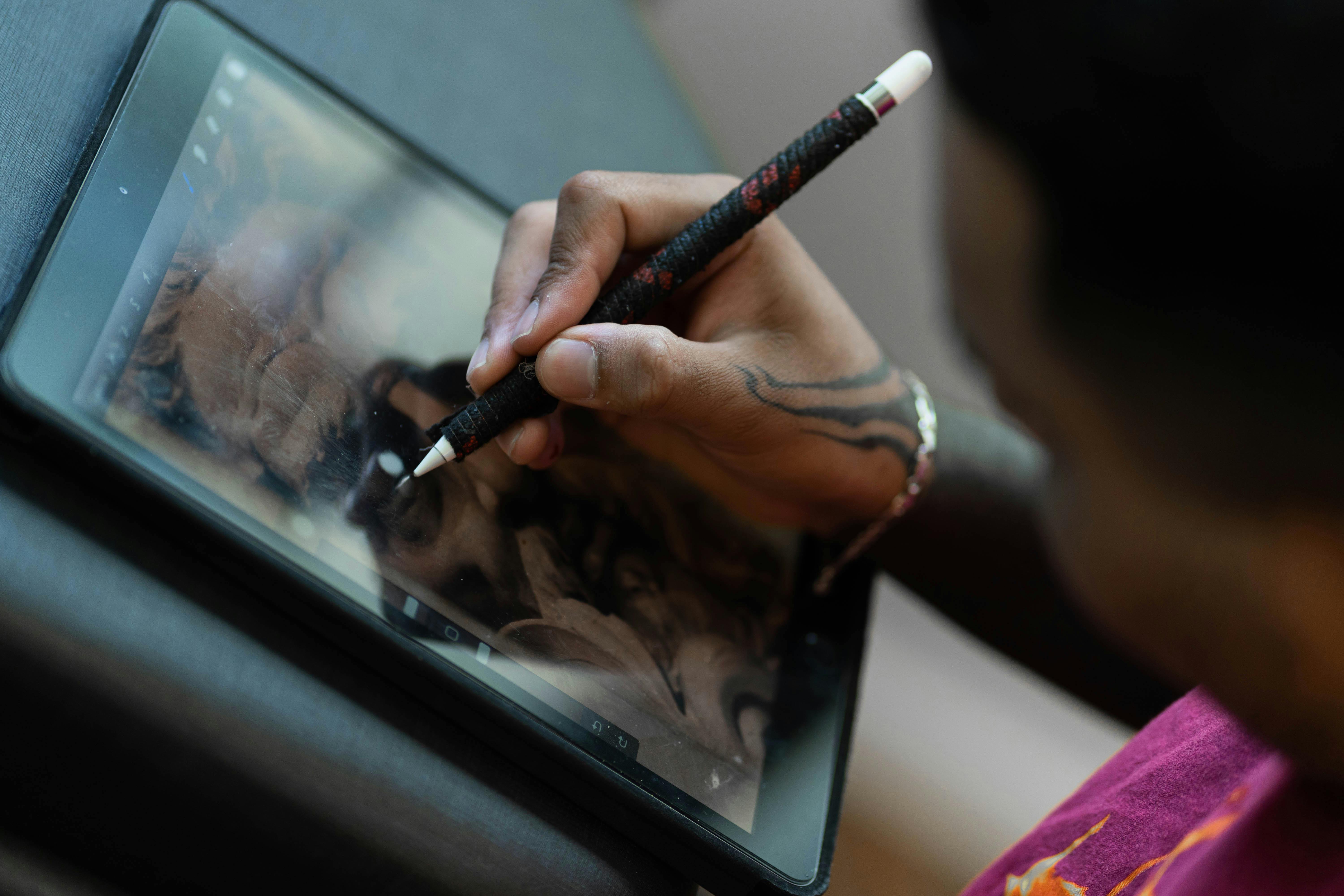 Close-up of hand drawing digital artwork on a tablet using a stylus.