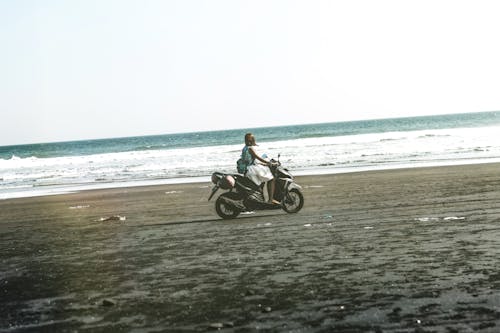 Woman Riding Black and Gray Motor Scooter on Beach
