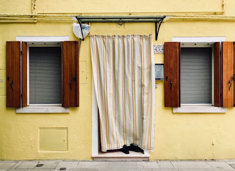 意大利威尼斯迷人的黄色立面，配有木制百叶窗和条纹窗帘