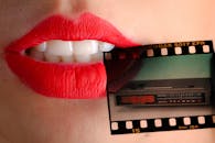 在一个创意构图中，红色嘴唇的艺术特写镜头手持一卷老式电影胶片