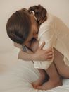 Woman Sitting on Bed Curled Up and Hugging Her Knees To Chest