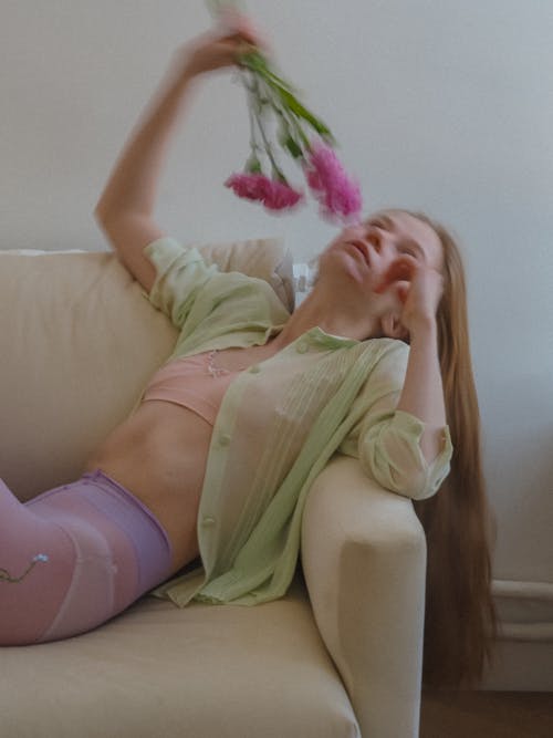 Woman Lying Down on the Sofa While Holding Flowers