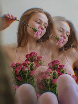 Artistic double exposure of a woman holding pink roses, creating a dreamy effect.