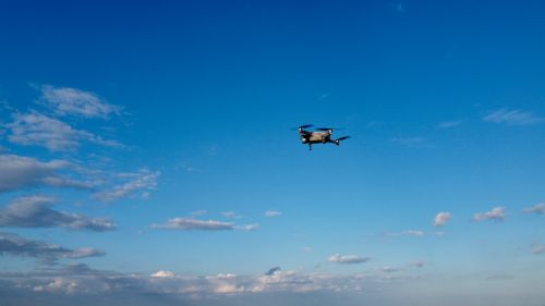 Free Drone soaring high in a bright blue sky with scattered clouds over England. Stock Photo