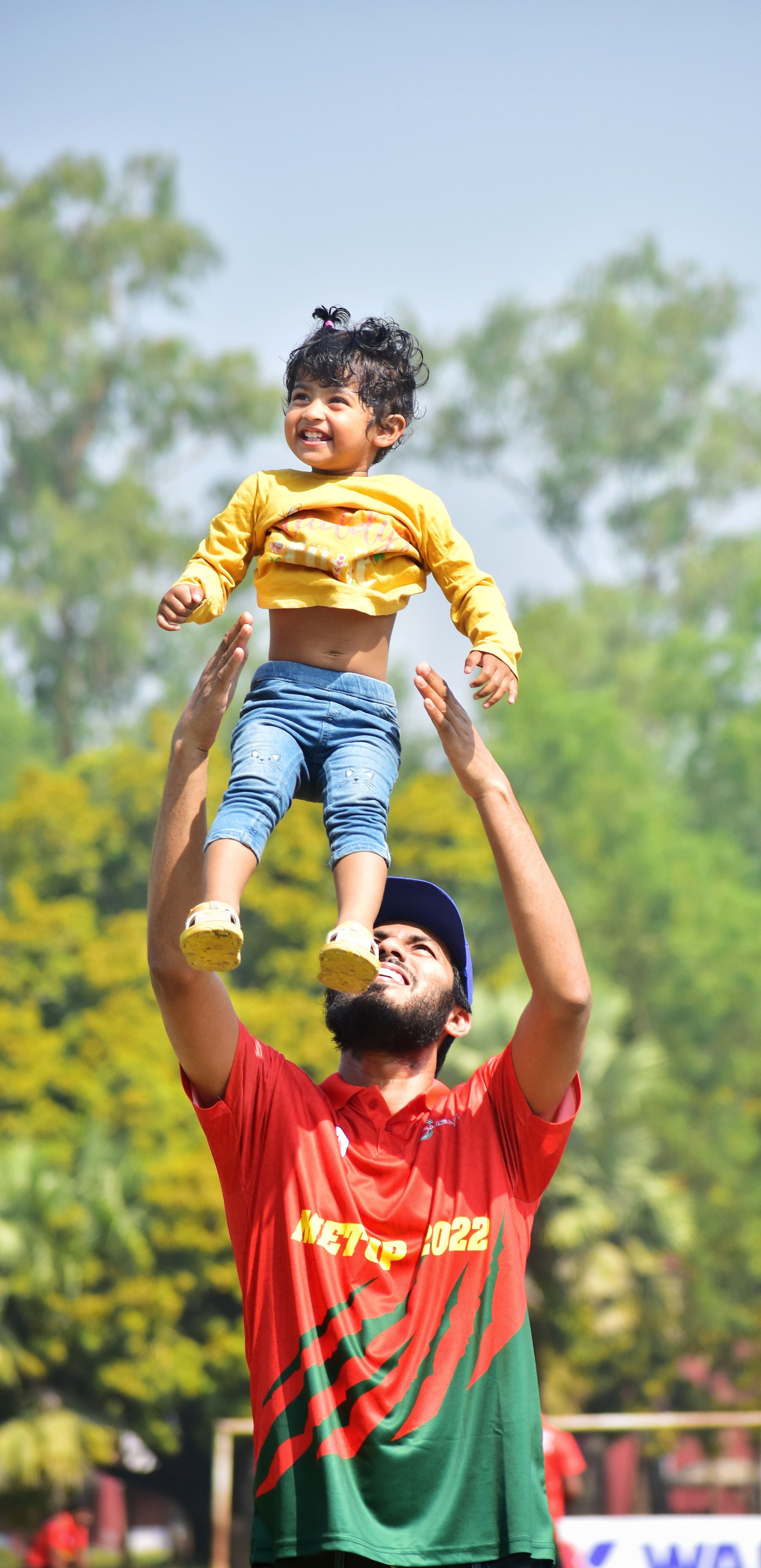 Happy father lifting his child outdoors in a park in Rajshahi, Bangladesh.