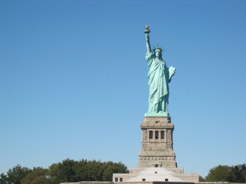 Free Iconic Statue of Liberty standing majestically under a clear blue sky in New York City. Stock Photo