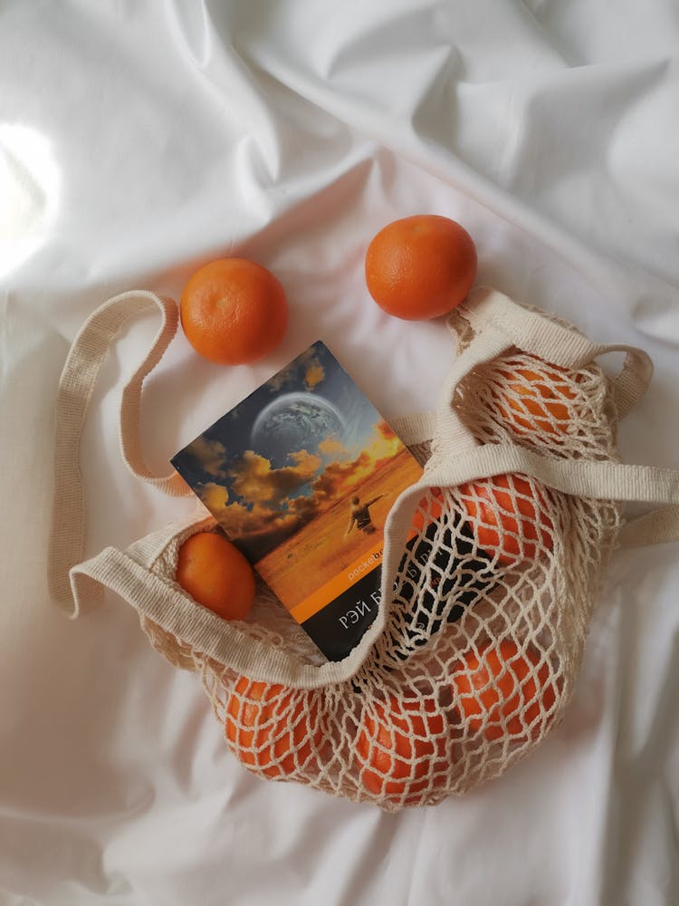 Top View Of Oranges And A Book In A Net Bag