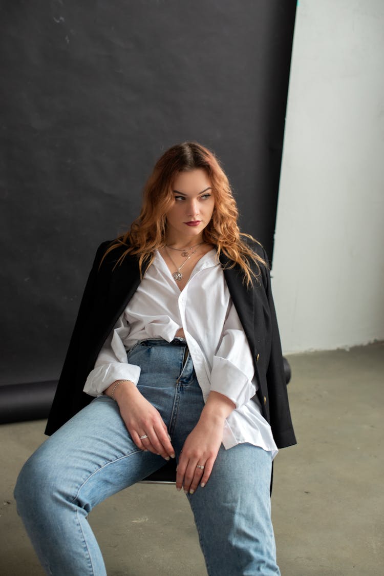 Girl With Red Long Hair Sitting In Chair In Casual Pose