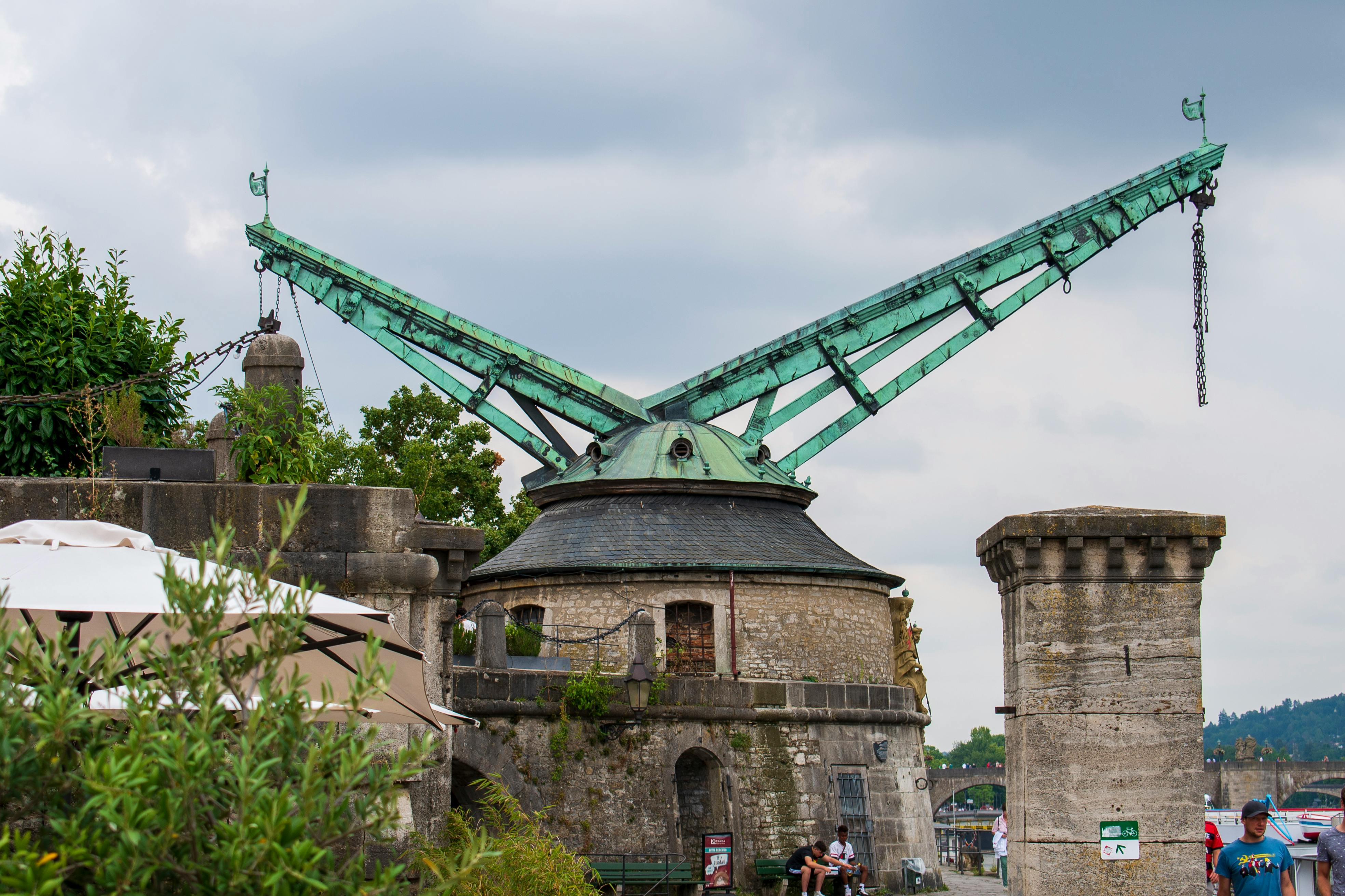 green copper vintage old crane by the main river in the old part of town wurzburg on a sunny day in summer