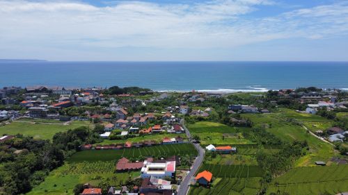 Free A beautiful aerial view of a village on Bali's coastline with lush greenery and the ocean in the background. Stock Photo