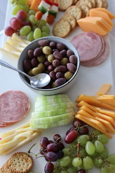 A beautifully arranged charcuterie board featuring olives, cheeses, and sliced meats.