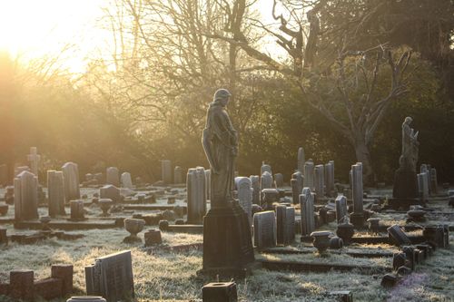 Free A serene cemetery with frosty tombstones and statues under soft morning sunlight, evoking tranquility. Stock Photo