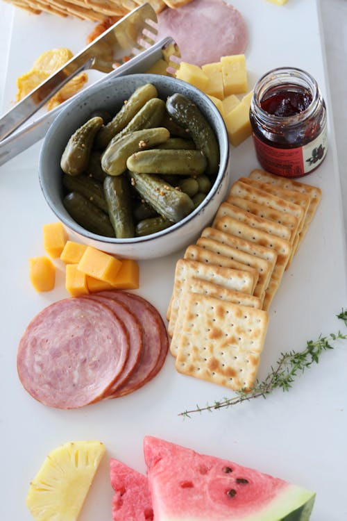 Free Dill Pickles in a Bowl and Crackers on a White Surface Stock Photo