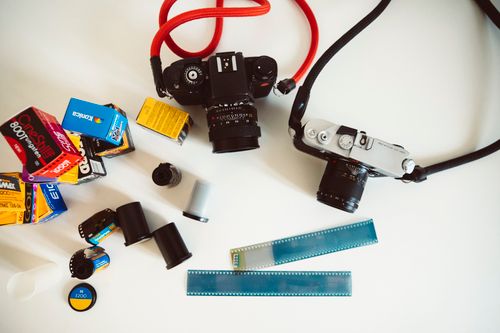 Free A collection of vintage film cameras and film rolls on a white surface, showcasing classic photography equipment. Stock Photo