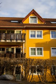 Charming yellow wooden house exterior with balcony, located in Oslo, Norway.