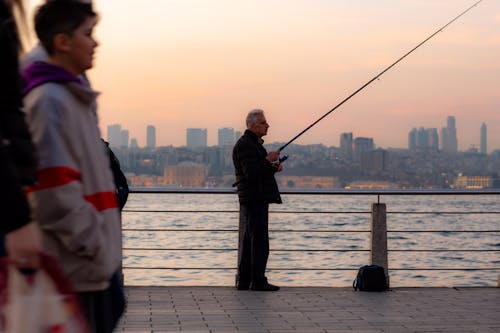 A Man Standing on the Shore Holding a Fishing Rod · Free Stock Photo