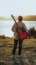 Man with Guitar on His Back Looking Out Into Lake