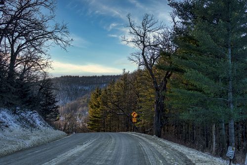 Free A winding rural road through snowy forests in Minnesota captured during a serene winter day. Stock Photo
