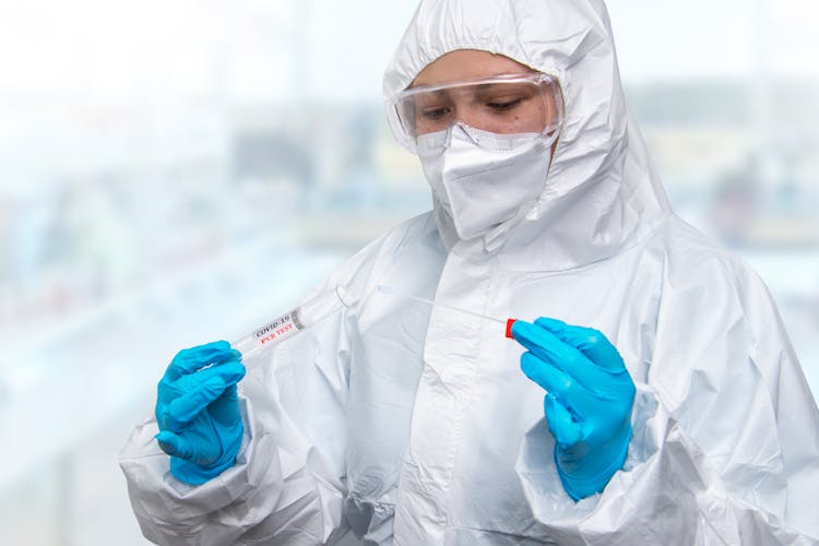 
A Person Wearing A Personal Protective Equipment Testing A Swab