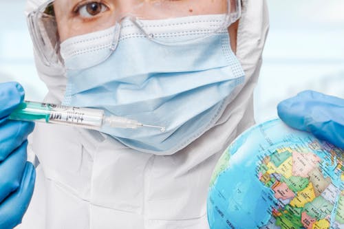 Free Person Wearing Surgical Mask Holding Syringe and Globe  Stock Photo