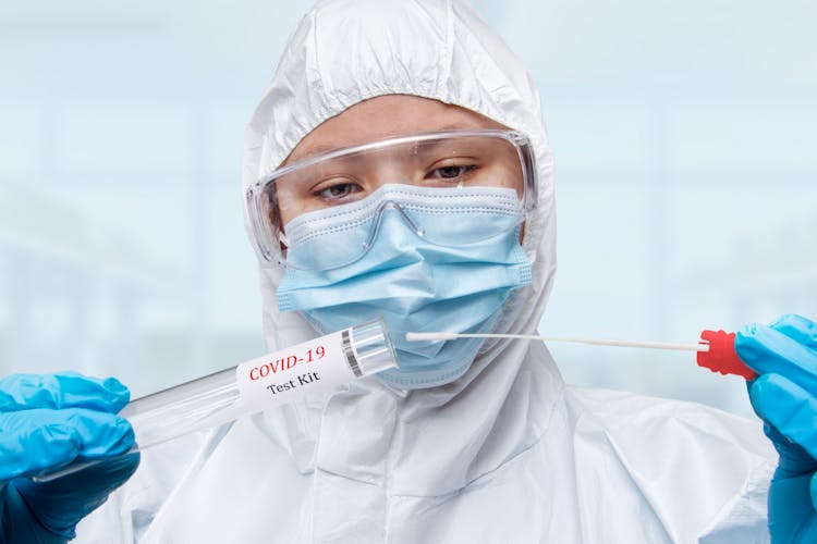 A Person In A PPE Holding A Nasal Swab