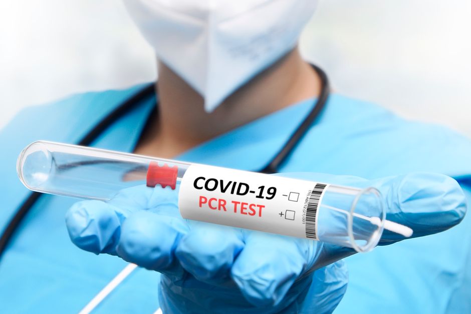 Medical professional in protective uniform holding a COVID-19 PCR test tube, exemplifying healthcare precision.