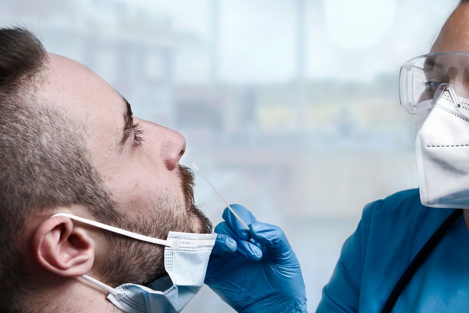 Healthcare professional administering a COVID-19 swab test to a patient indoors.