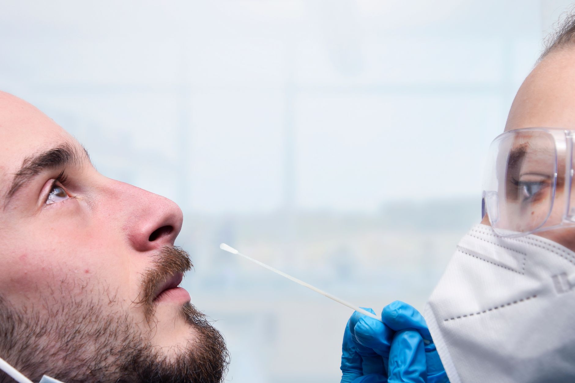 Healthcare worker administering a nasal swab test for COVID-19 detection indoors.