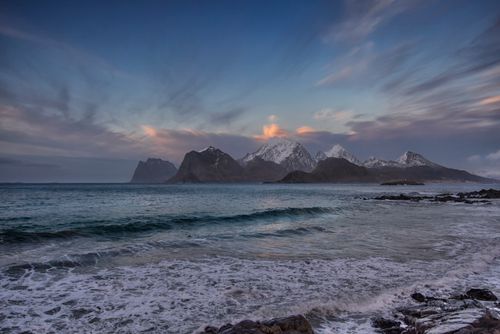 Free Breathtaking view of Norwegian coastline with snowy mountains and serene sea waves at dusk. Stock Photo