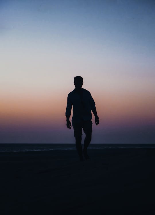 
A Silhouette of a Man Walking at a Beach