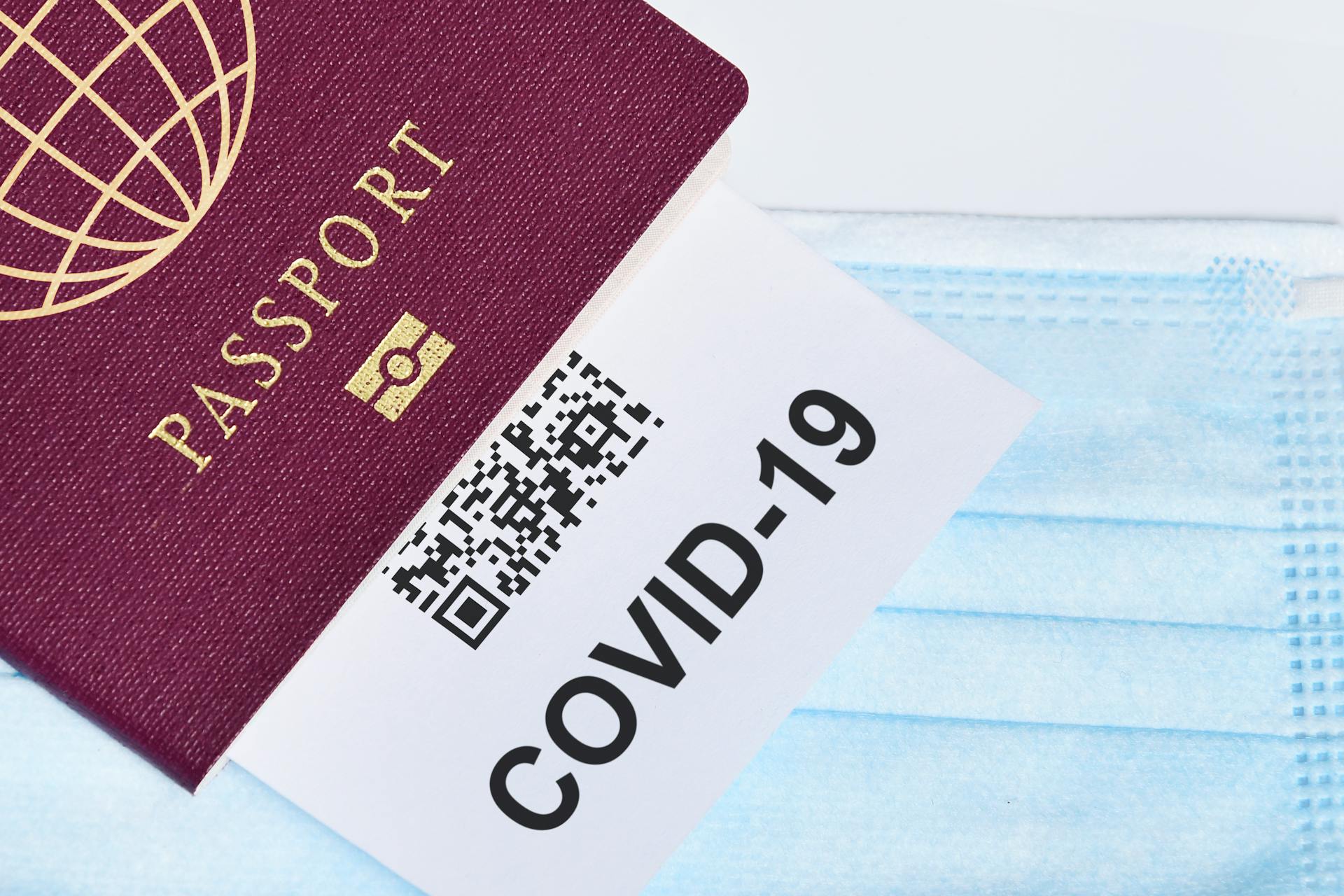 Close-up of a passport with a COVID-19 QR code and surgical mask, representing travel during the pandemic.