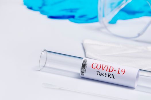 Close-up of a COVID-19 test kit with swab on a white surface, ideal for healthcare theme.