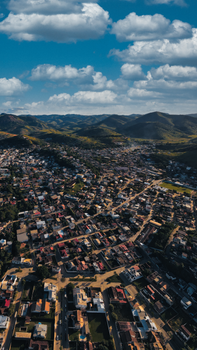 Breathtaking aerial view of a city surrounded by rolling hills under a cloudy sky.