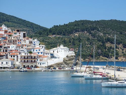 Free Idyllic view of Skopelos town with colorful buildings and yachts under a clear blue sky. Stock Photo