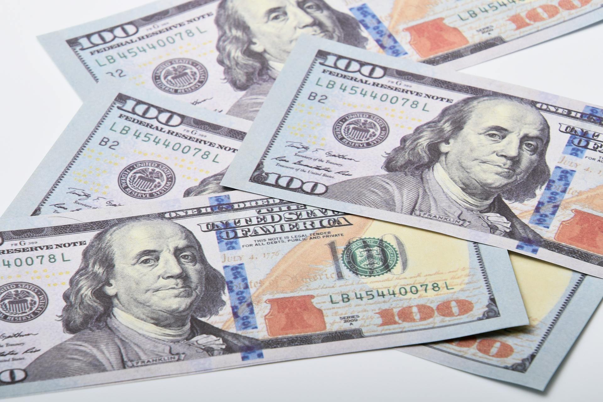 High-quality image of US $100 bills scattered on a white surface. Ideal for financial themes.