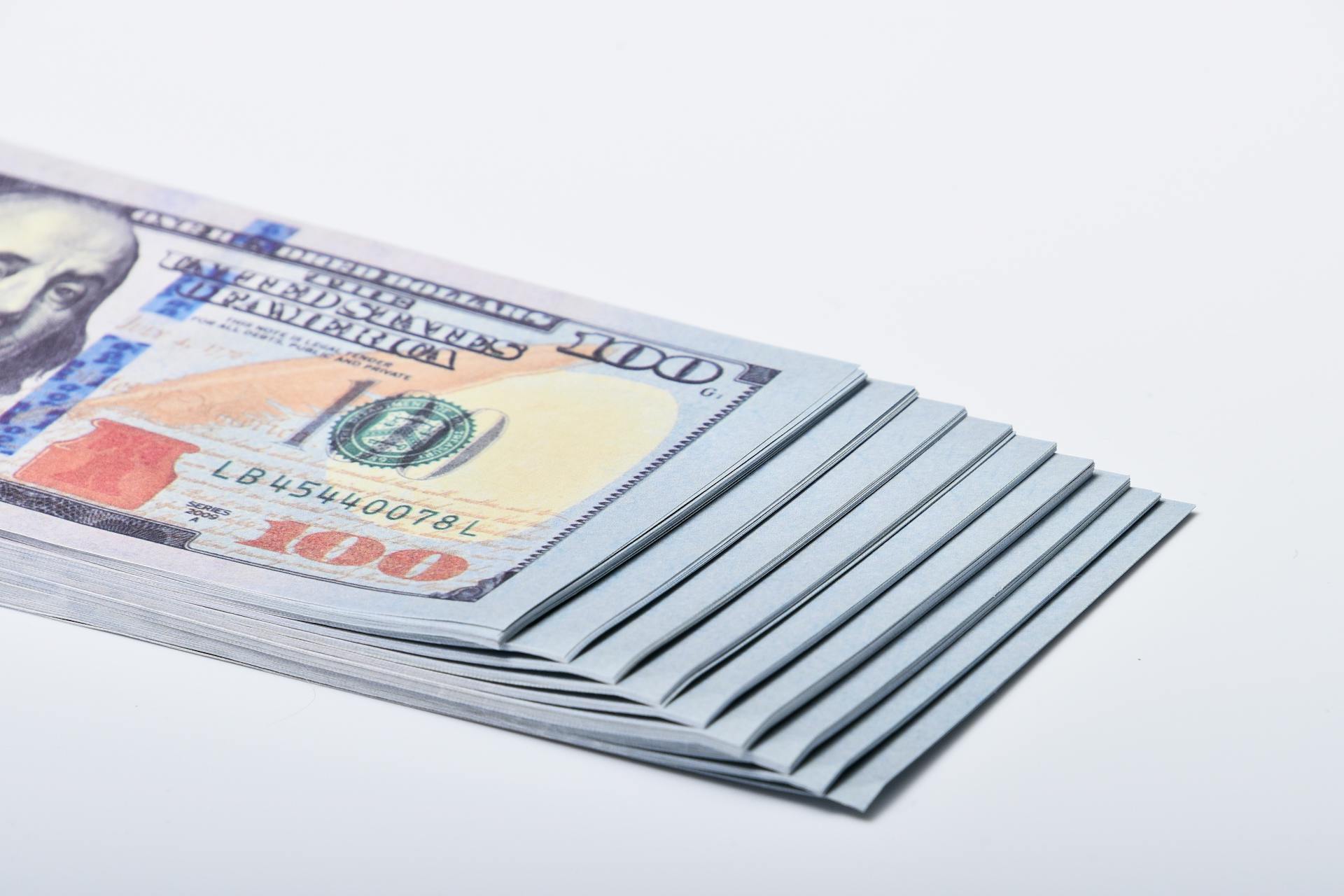 Close-up of stacked US dollar banknotes on a white surface, symbolizing wealth and finance.