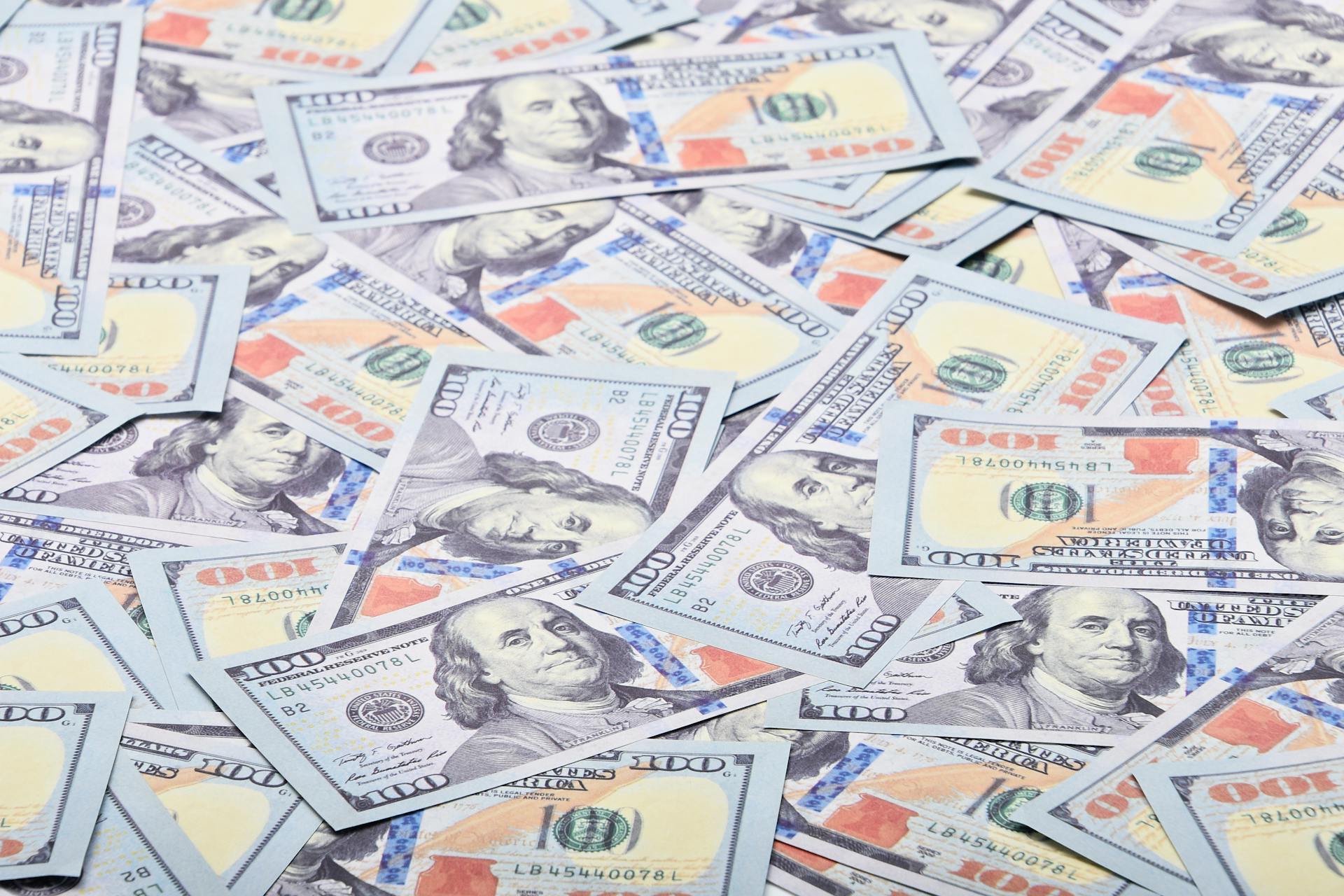 Close-up view of scattered US hundred dollar bills, showcasing paper currency.