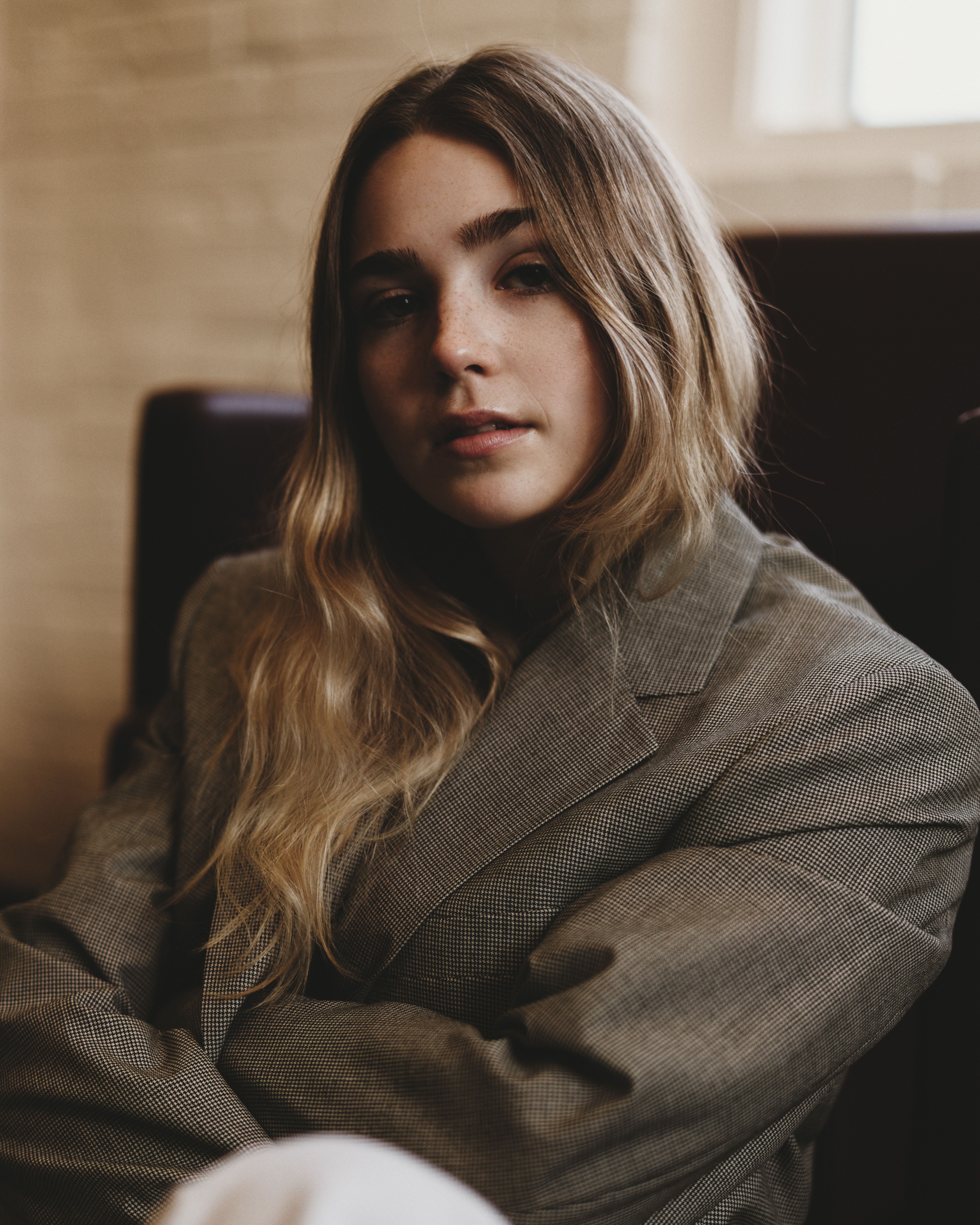 Portrait of a young woman with long hair wearing a stylish jacket, exuding confidence and poise.