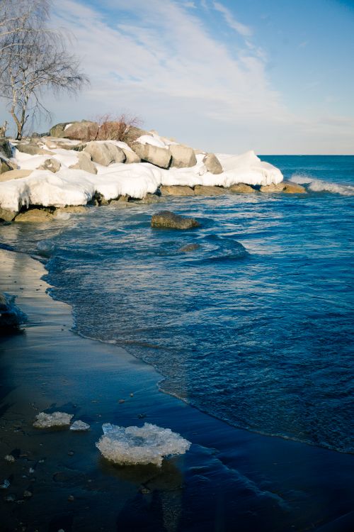 Free A serene winter scene of a snow-covered beach and icy waters in Toronto, Canada. Stock Photo
