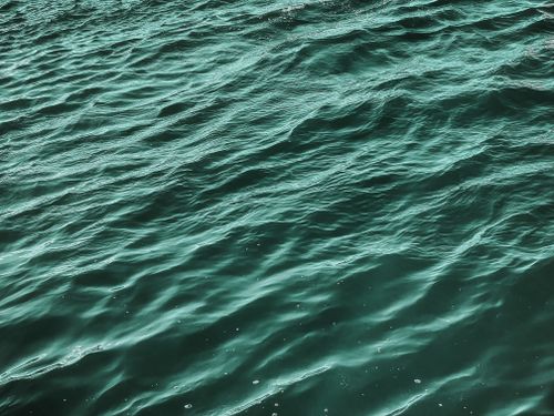 Free A calming view of ocean waves with subtle ripples and vibrant teal hues, ideal for backgrounds. Stock Photo