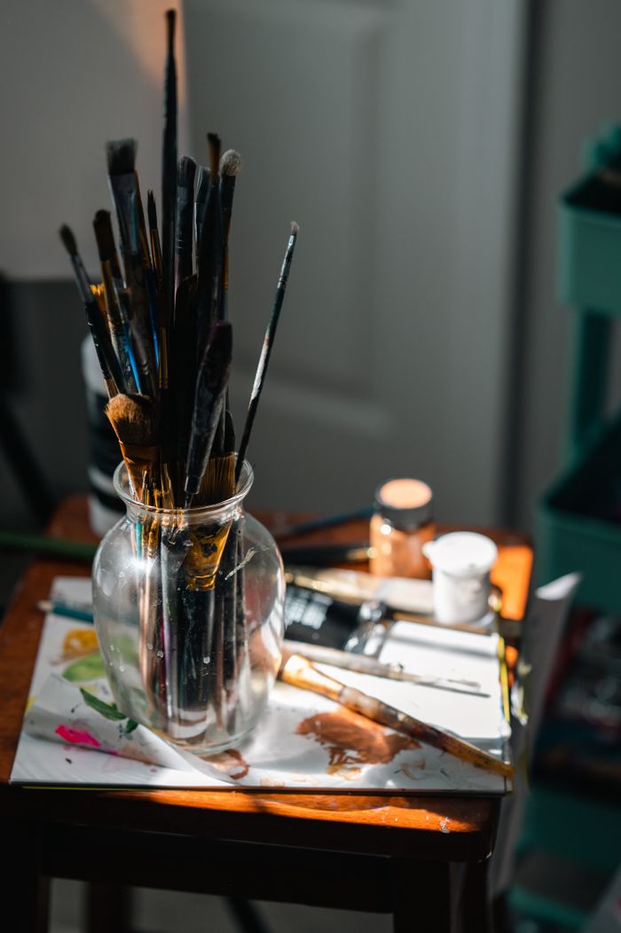 A sunlit bench with brushes in a glass jar