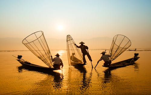 Three Men Riding Boats on Body of Water