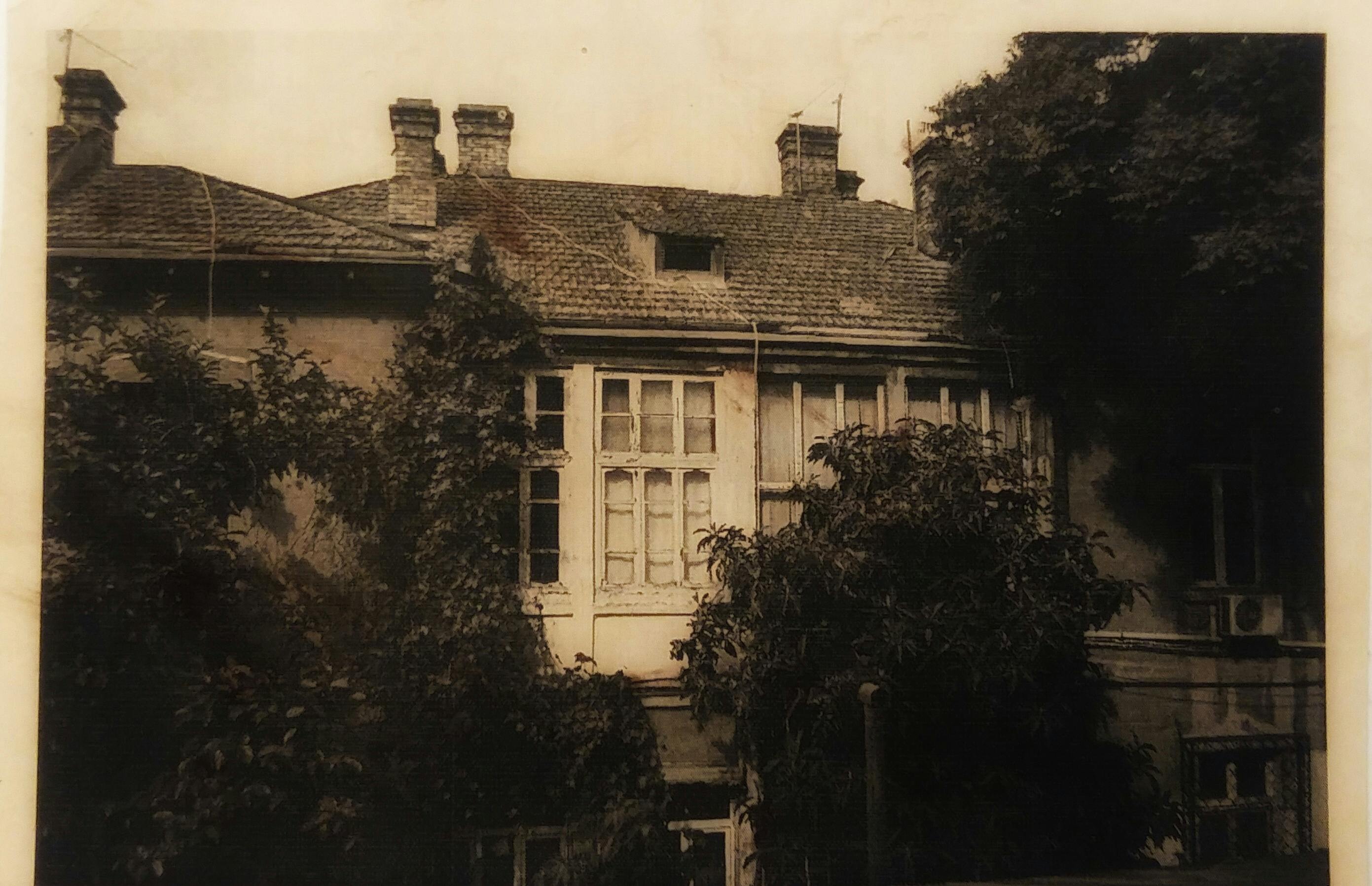 A sepia-toned vintage photograph of an old building with trees.