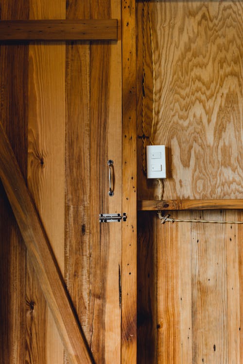 A White Light Switch On Wooden Wall Beside a Door Handle