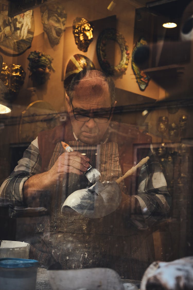 A Man Painting A Mask