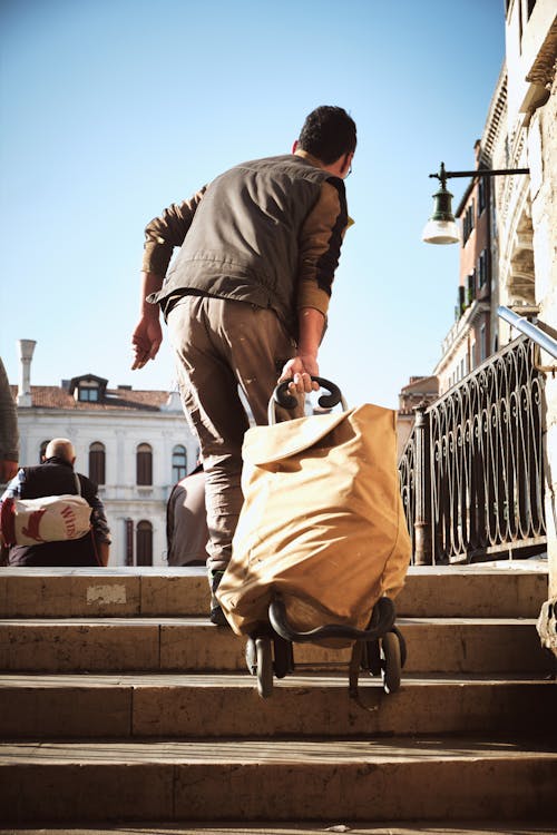 Free Back View of a Man Dragging a Bag Through the Stairs Stock Photo