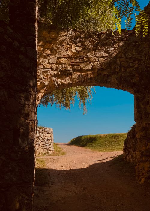 Free Elegant stone archway leading to a sunny dirt road in Arona, Piemonte, Italy. Stock Photo
