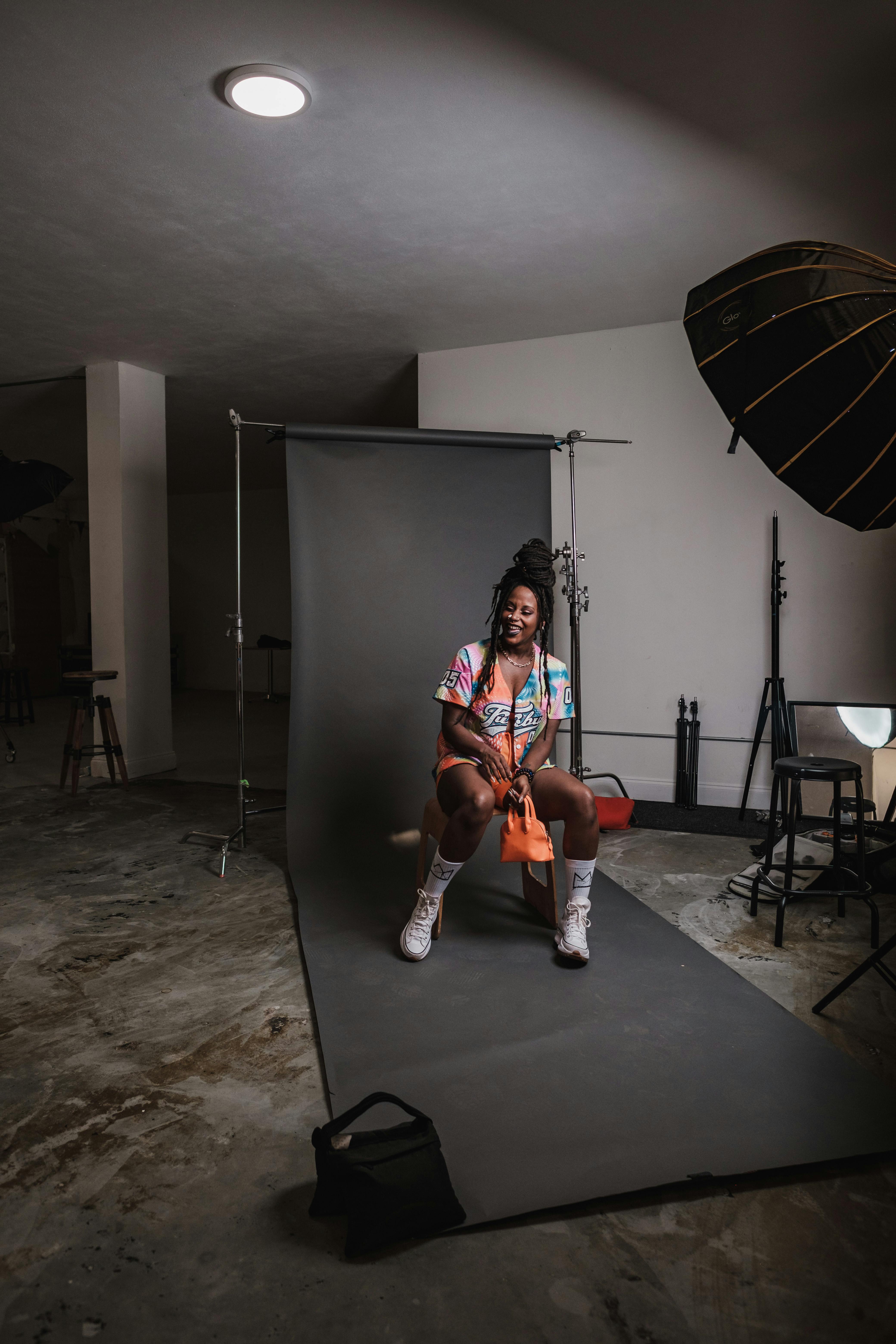 A vibrant portrait of a smiling woman with dreadlocks in a studio setting.